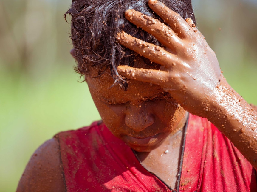 Junior rubs mud into his skin.