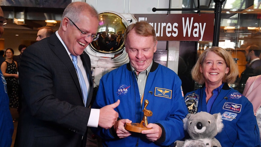 Scott Morrison smiles and gives the thumbs up as a NASA astronaut holds a Gold Logie. Another NASA astronaut holds a plush koala