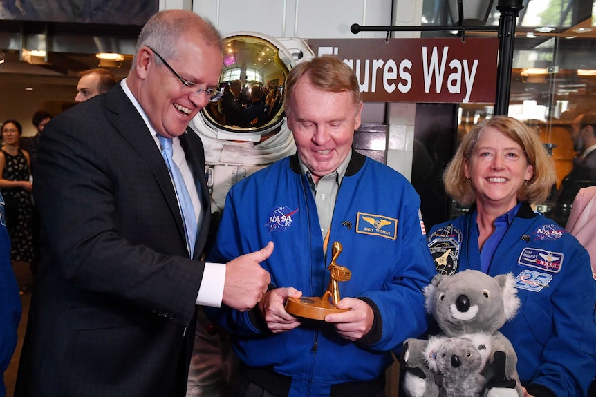 Scott Morrison smiles and gives the thumbs up as a NASA astronaut holds a Gold Logie. Another NASA astronaut holds a plush koala