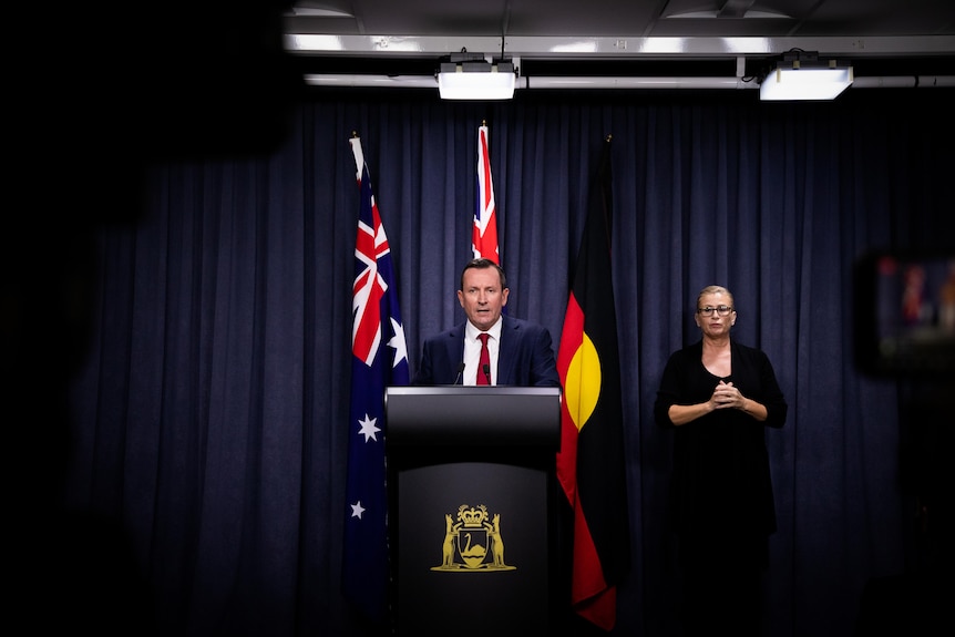 A centered shot of Mark McGowan doing a press conference with an interpreter standing next to him