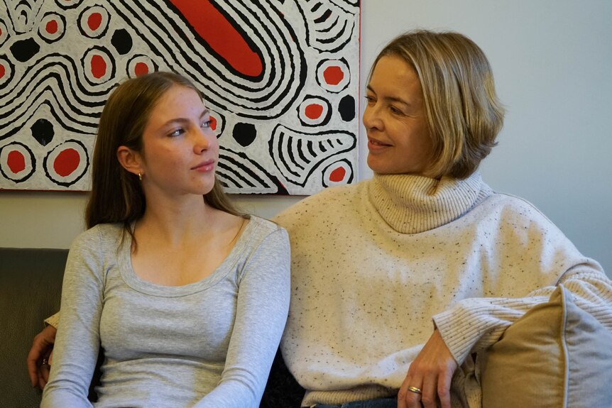 a woman and a teenage daughter look at each other sitting on the couch