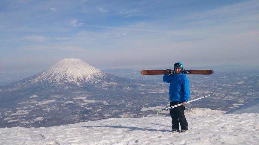 A man standing on top of a ski slope in Japan.