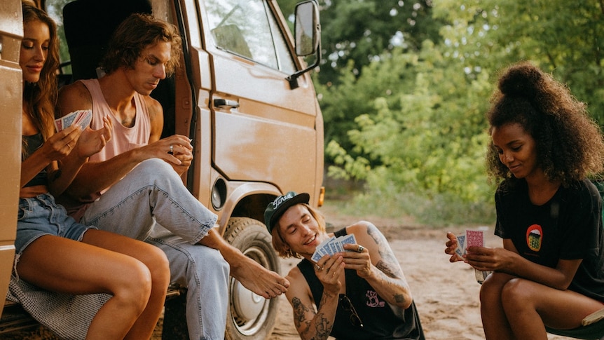 Group of friends in their 20s in a campervan playing cards.