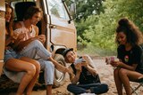 Group of friends in their 20s in a campervan playing cards.