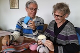 two men hold balls of knitting yarn
