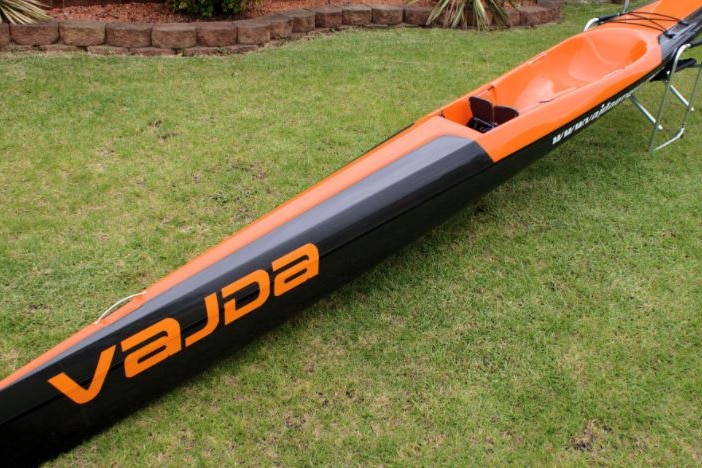 Black and orange surf ski lying on a lawn