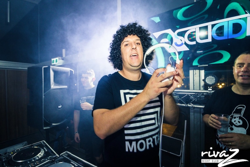 A DJ holds a headset in a regional nightclub