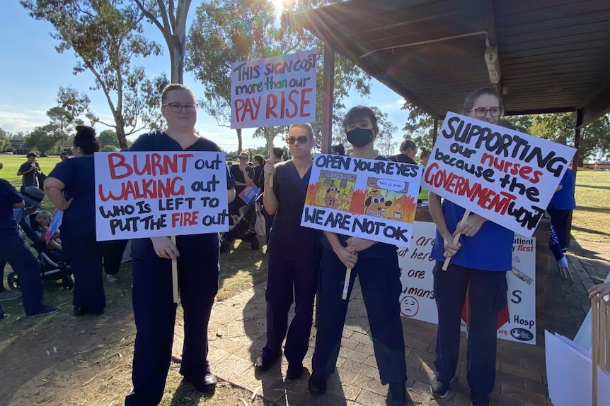 Women standing holding signs in a park