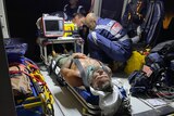 a man in  stretcher, being cared for by paramedics