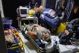a man in  stretcher, being cared for by paramedics