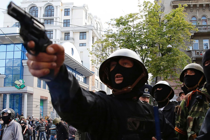 A pro-Russian activist aims a pistol at supporters of the Kiev government during clashes in the streets of Odessa in 2014.