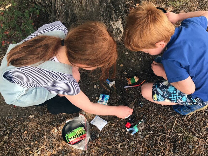 Two children with plastic toys they found in a hidden container.