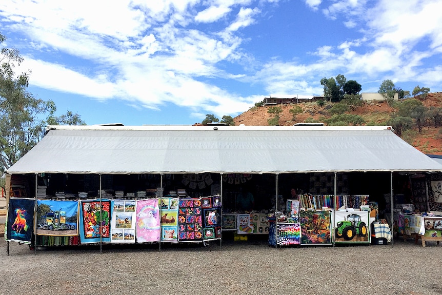 A large awning is pulled in front of bus and forms a pop-up shop filled with colourful fabrics