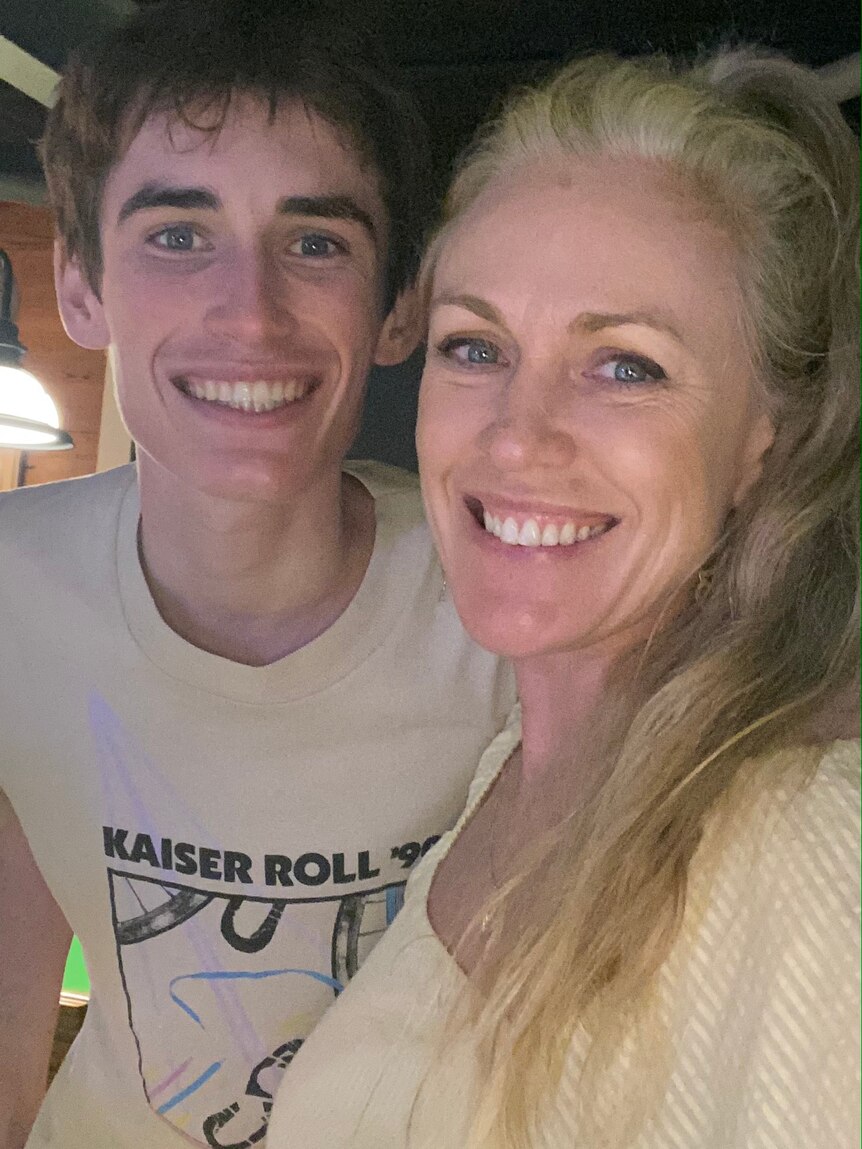 Portrait selfie of a mother with long sandy blonde hair with her teenage son. Both have big smiles.