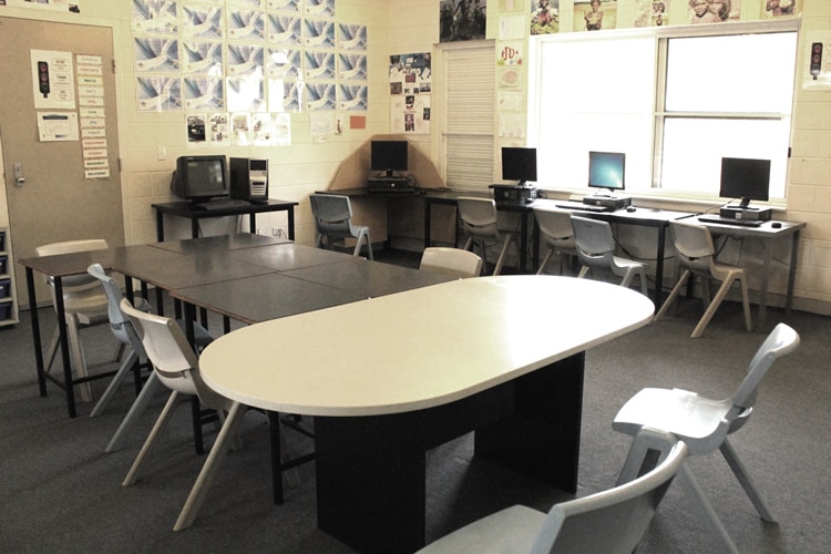 A classroom with plastic chairs, a whiteboard and few computers.