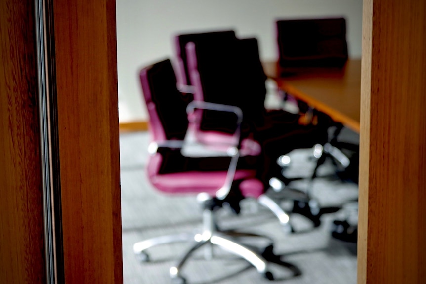 Purple chairs seen through a door in a boardroom.