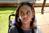 Denishar Woods sits in a wheelchair outside in hospital grounds with tubing attached to her nose.