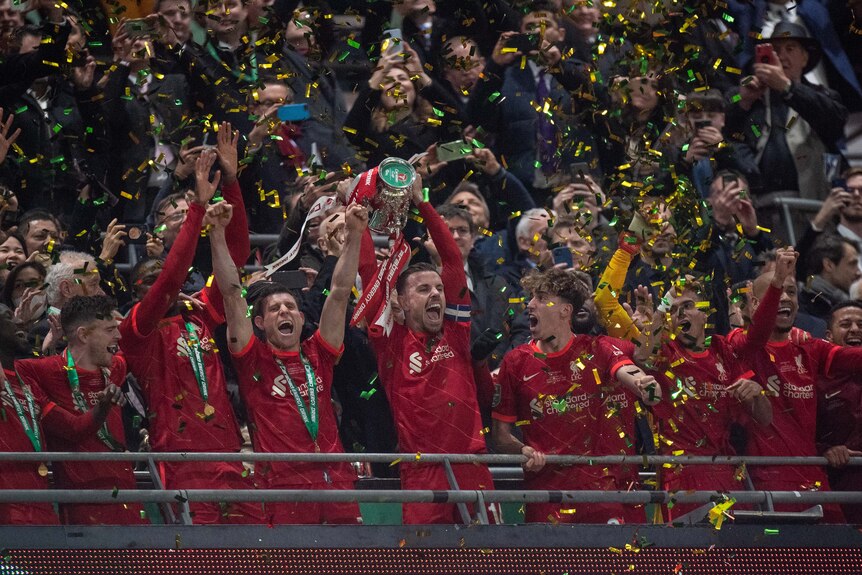 Liverpool celebra ganar la Copa Carabao sosteniendo el trofeo en alto en las gradas