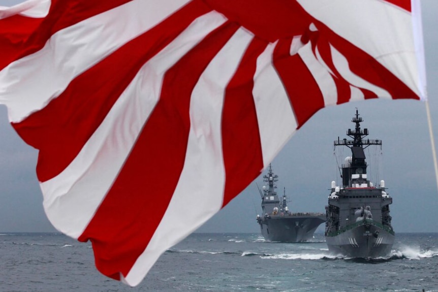 Two Japanese Maritime Self-Defense Force ships on the ocean with a red and white flag
