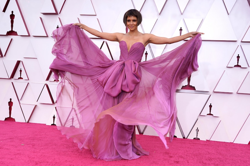 Halle Berry spreads out the layers of her purple dress for the cameras