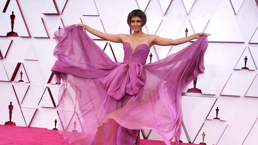 Halle Berry spreads out the layers of her purple dress for the cameras
