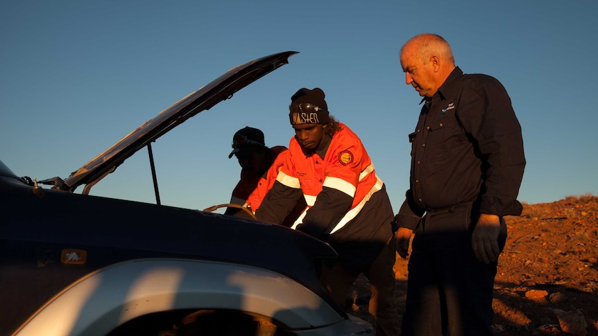 Three men look for car parts in a car graveyard outside Wiluna