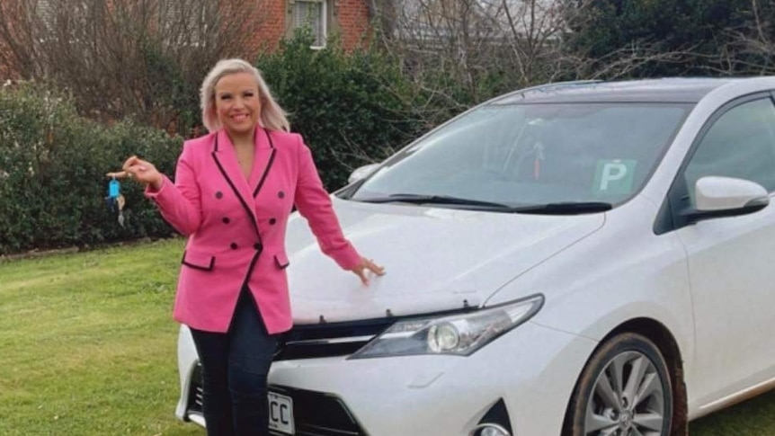 women standing next to her car smiling with keys in hand with P plates on her car