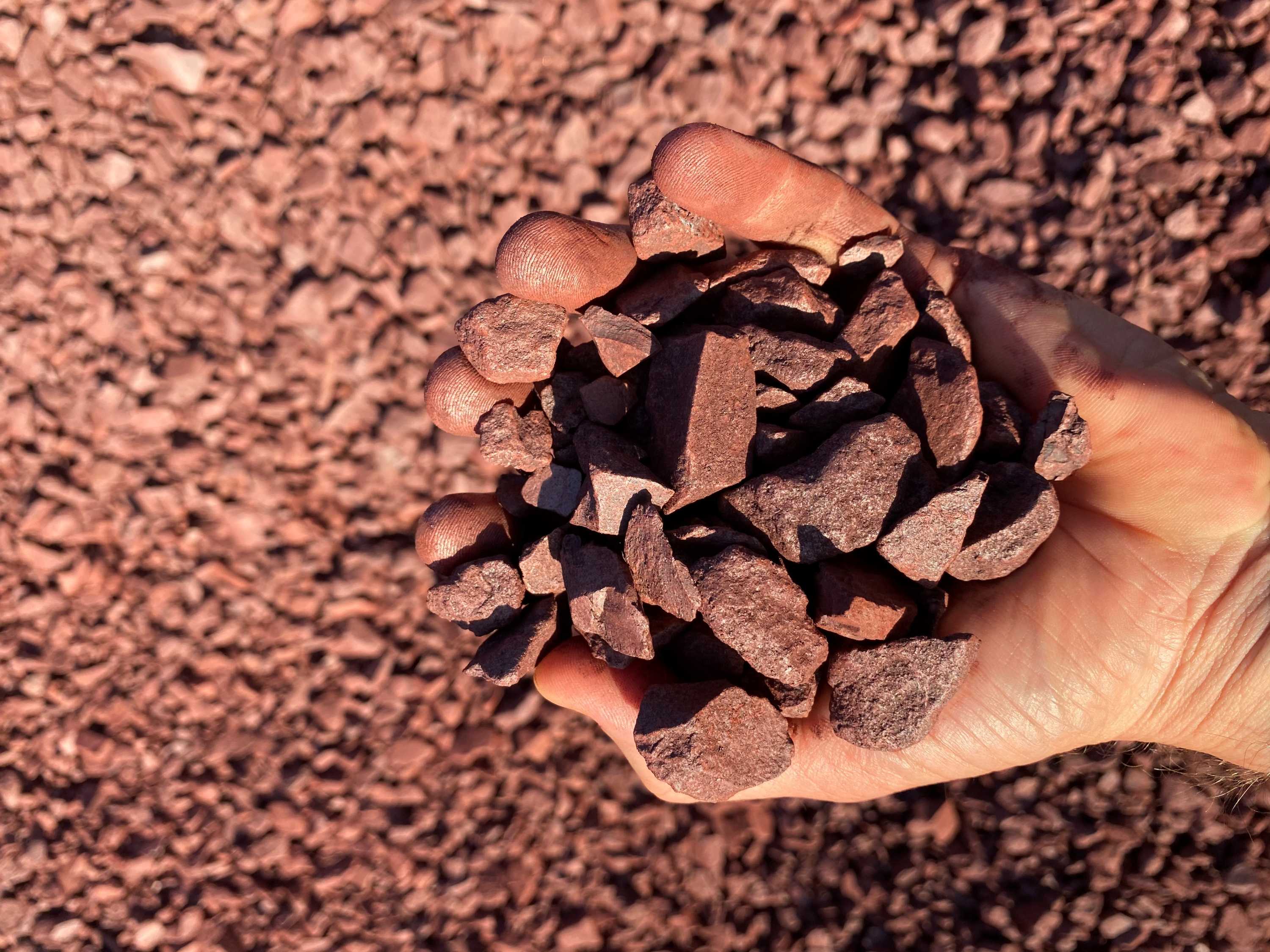 A man is holding a handful of iron ore in the NT.