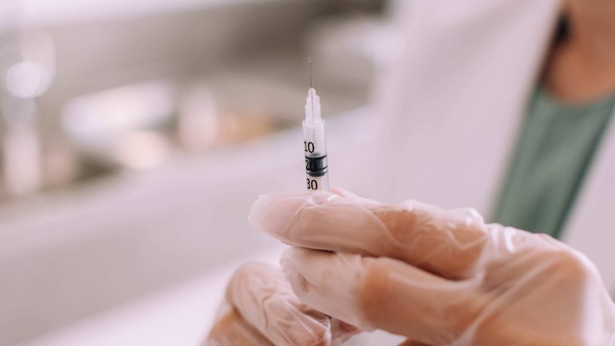 A young doctor is holding a medical syringe in the clinic.