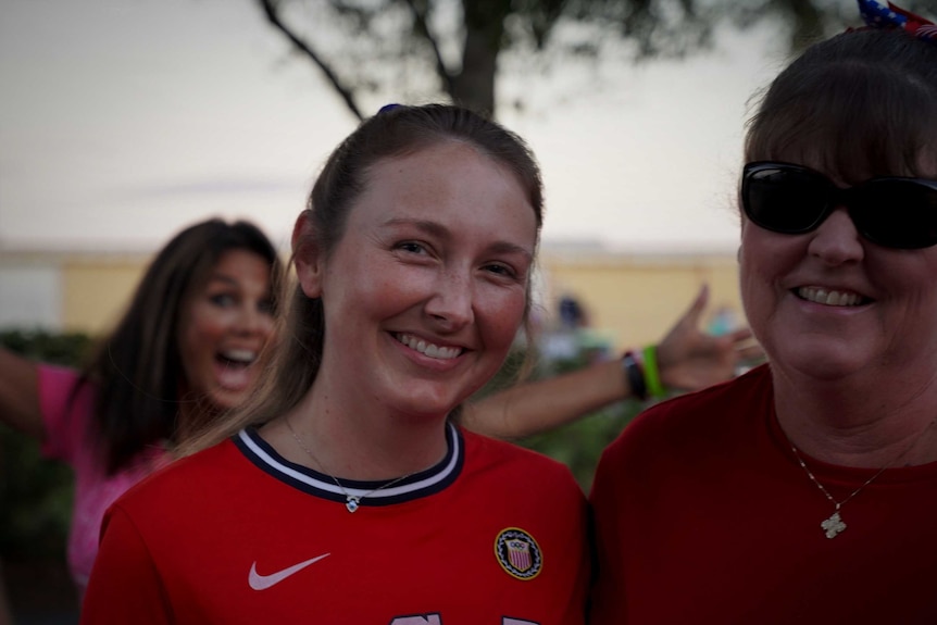 Two women smile for the camera, while another jumps in behind them