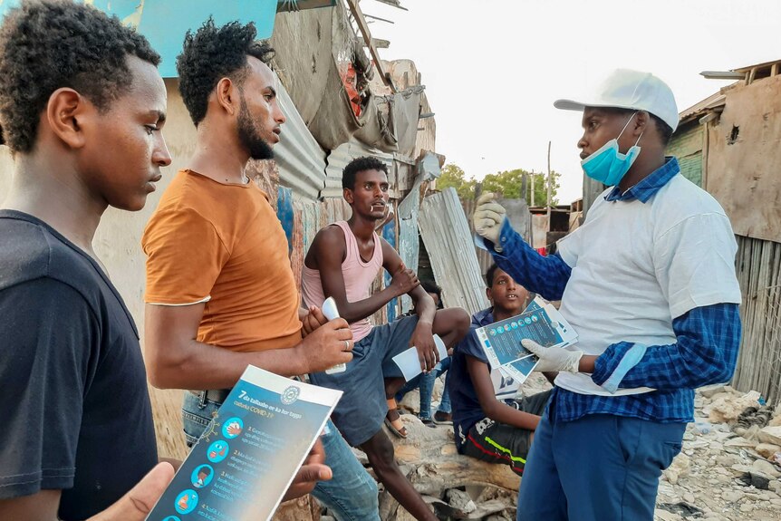Stranded Ethiopian migrants receive informational materials informing them how to protect themselves against the coronavirus.