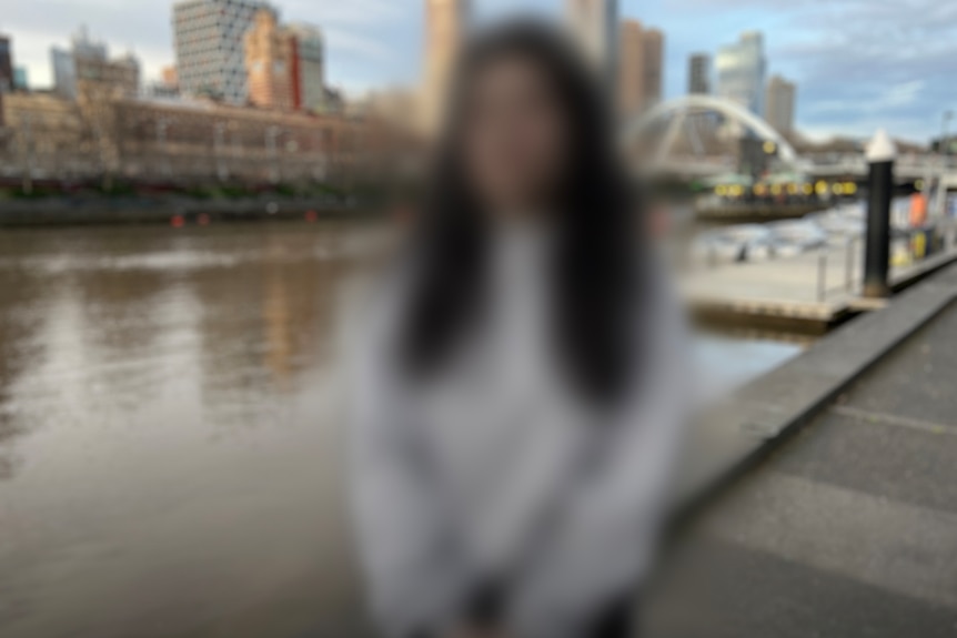 A woman stands near a river.