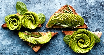 Avocado, sliced elaborately in the shape of flowers, on toast.