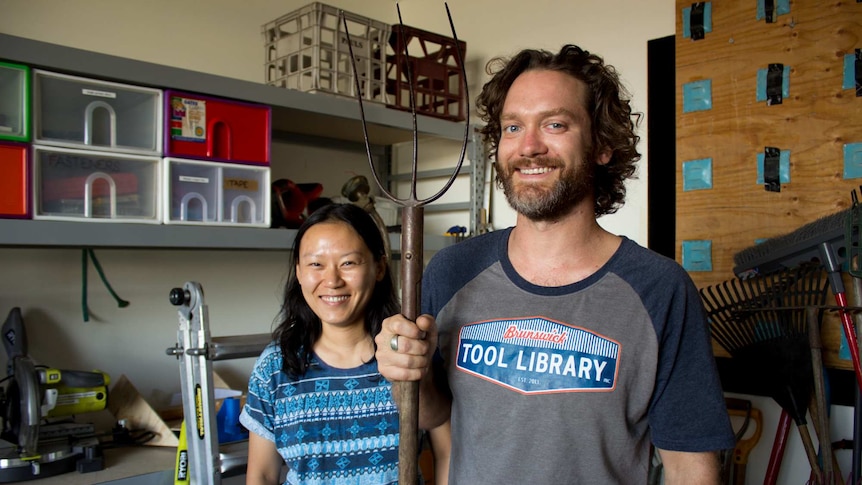 Two people stand in a room filled with tools.