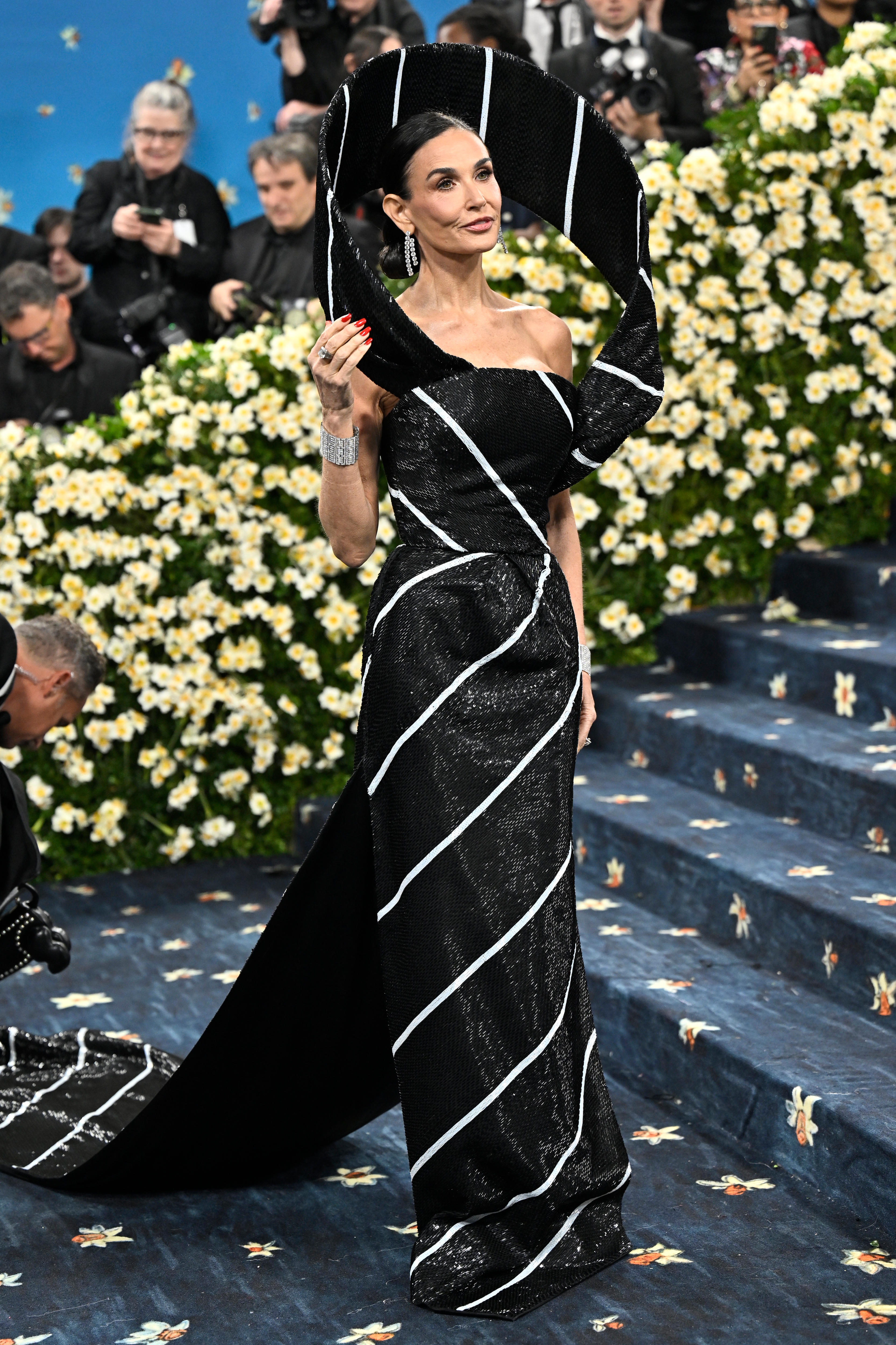 Demi Moore wearing a strapless black and white striped dress with a structured halo hovering behind her head