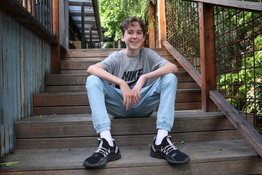 A young boy sits on the steps smiling