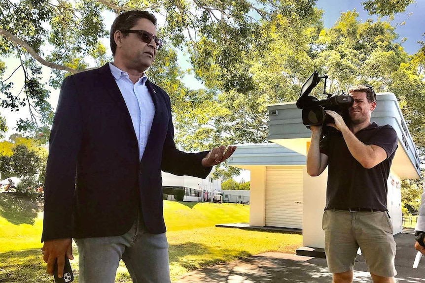 A man in sunglasses being filmed by a cameraman