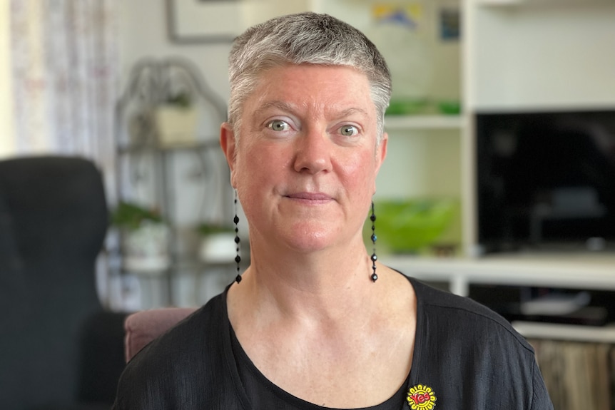 A middle-aged white woman with short grey hair sitting in a lounge room