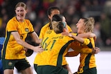 Matildas players hug Charli Grant after her goal against England.