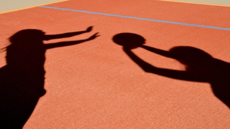 Shadows of netball player shooting a goal