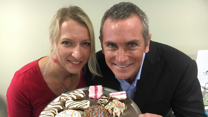 Emma and Russell Gibbons pose with a colourful plate of their dog biscuits that look just like human biscuits.