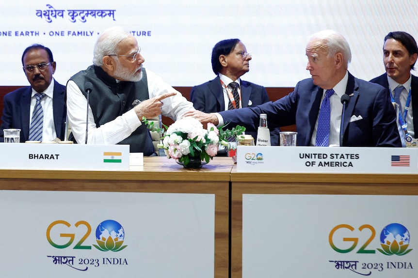 Narendra Modi and Joe Biden sit at a table side by side.