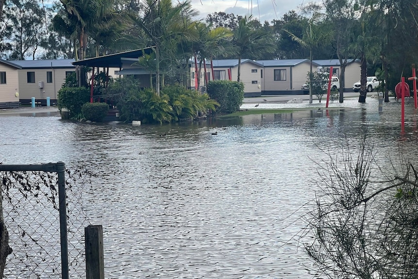 Floodwater surrounds cabins at a caravan park.