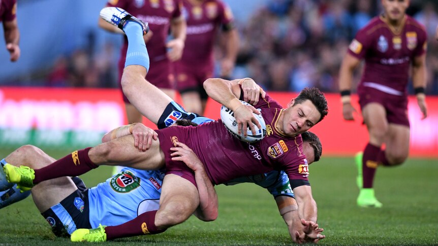Queensland's Cooper Cronk tackled by the Blues' James Maloney in State of Origin Game II