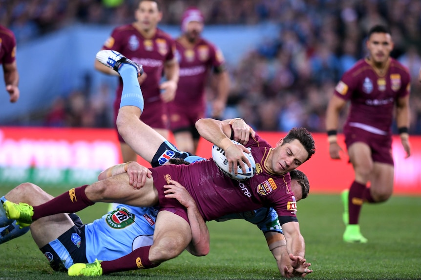 Queensland's Cooper Cronk tackled by the Blues' James Maloney in State of Origin Game II