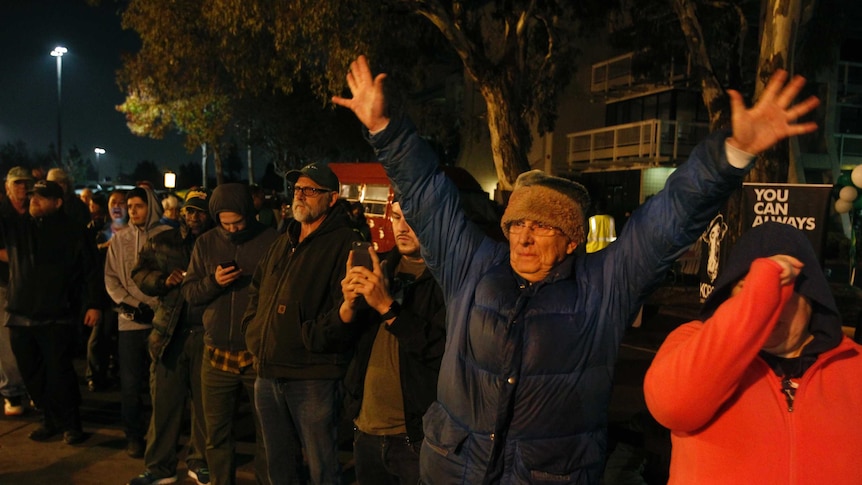 A man holds up his hands in celebration while waiting in a line outside an Oakland dispensary.