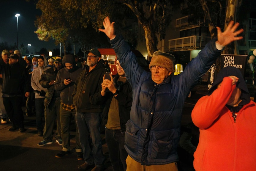 A man holds up his hands in celebration while waiting in a line outside an Oakland dispensary.