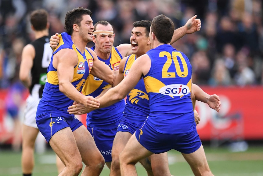 Eagles players hug each other after they beat the Magpies in the AFL grand final.