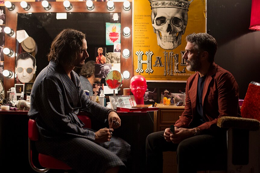 Leonardo Sbaraglia and Asier Etxeandia sit facing each other while seated at a dressing room table.