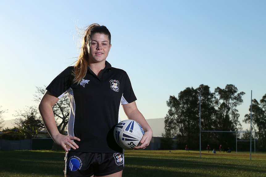 Kaarla Cowan stands on a football field holding a football.